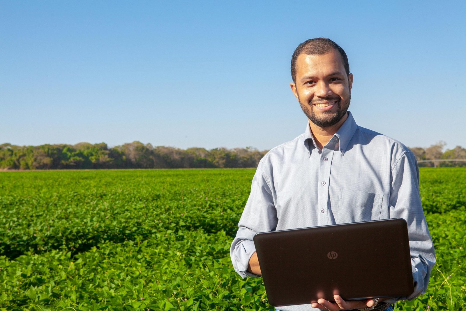 The Top 3 Drone Sensors Every Farmer Should Know About 1 A farmer in Santo Antônio de Goiás smiling while using a laptop in a lush field.